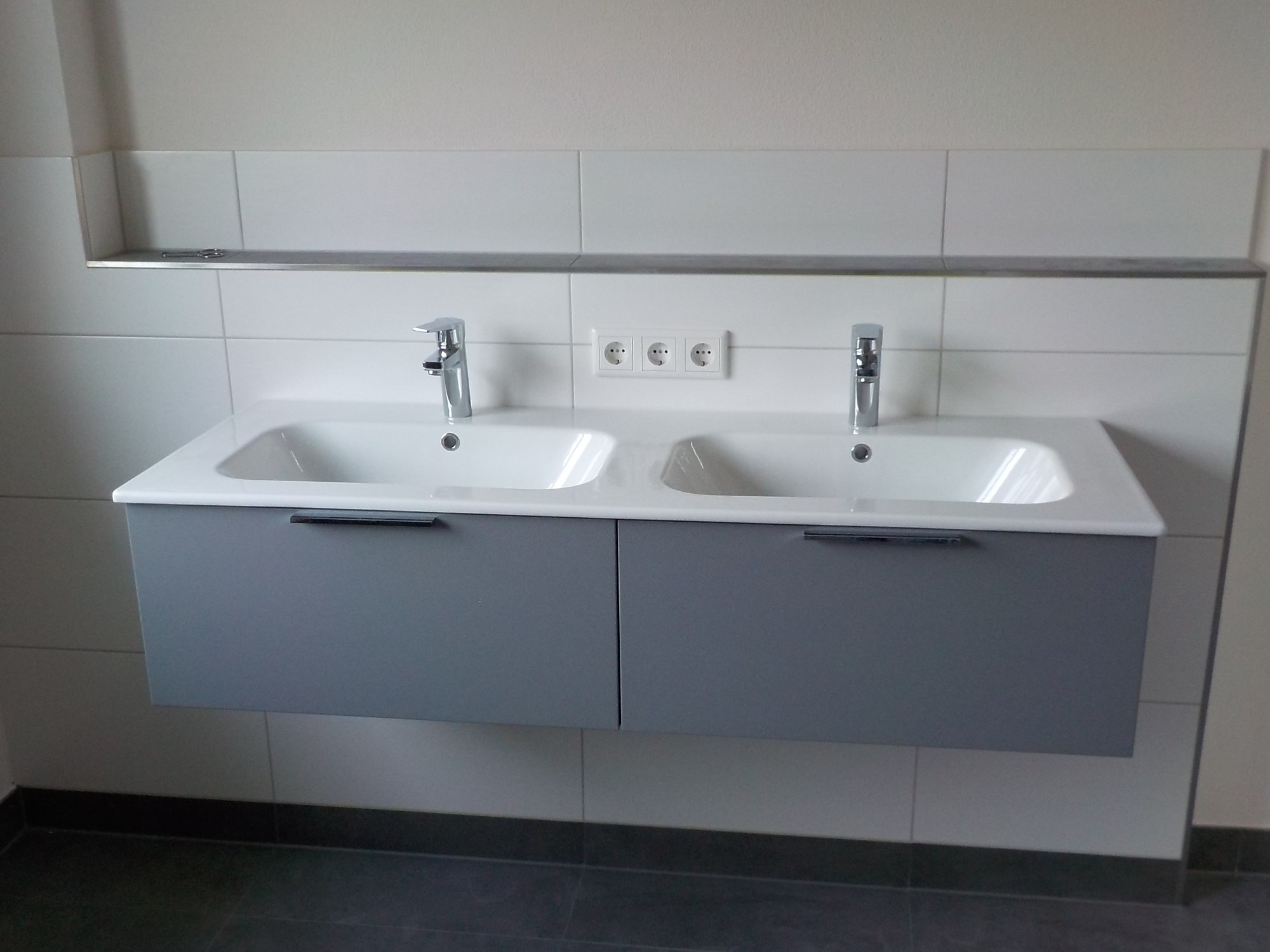 Doppelwaschtisch mit grauem Unterschrank und zwei Armaturen