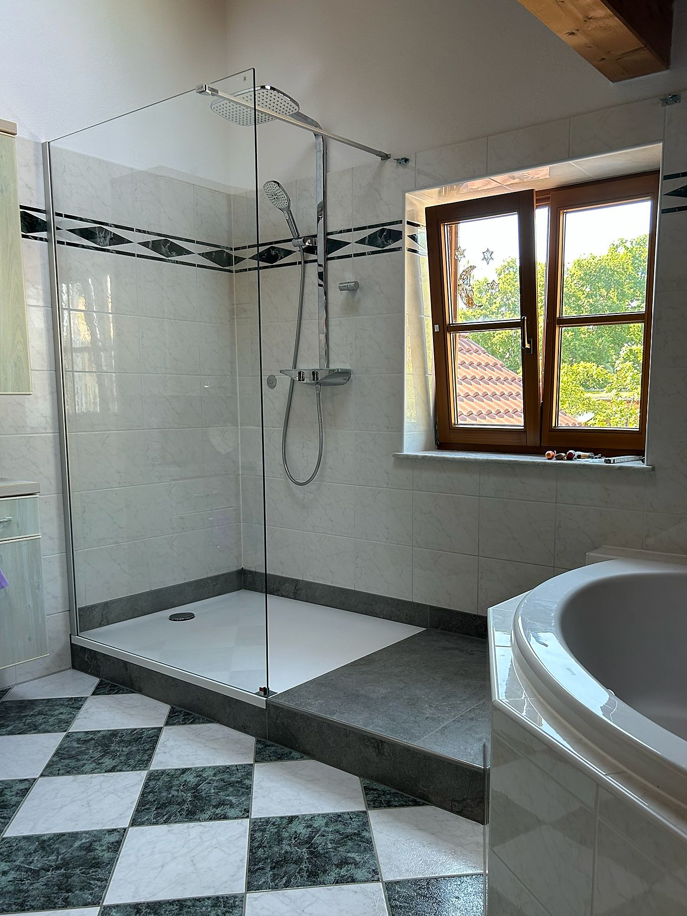 Große Dusche mit Glaswand, Regenbrause und Thermostat neben einer Eckbadewanne
