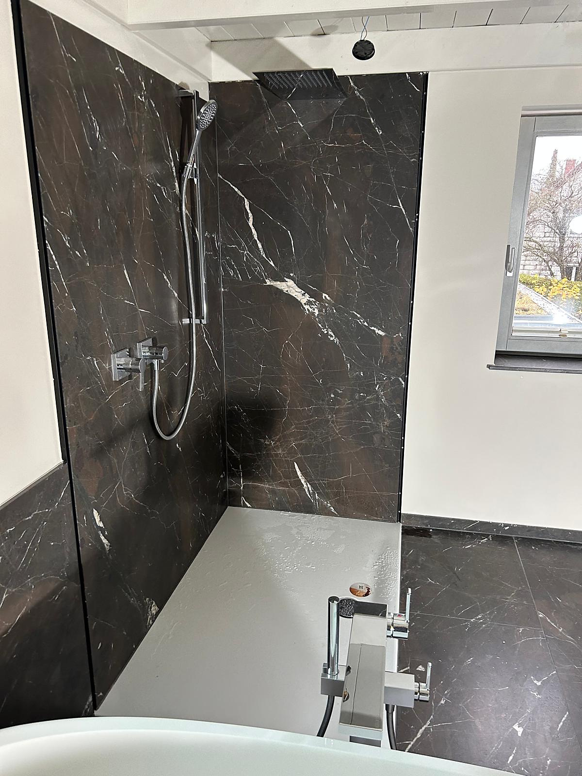 Dusche mit dunklen Marmor-Wandplatten, Regenbrause und Handbrause