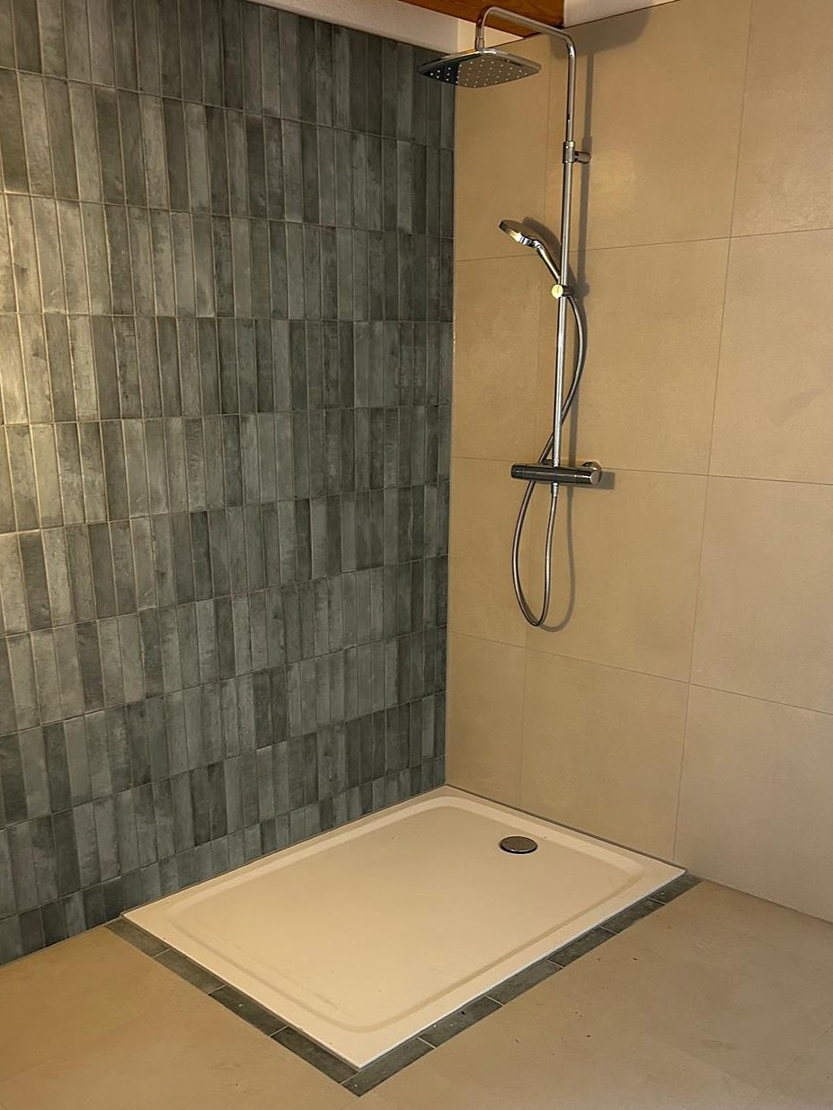 Dusche mit flacher Duschwanne, Thermostat-Duschsystem und grauen Stäbchenfliesen