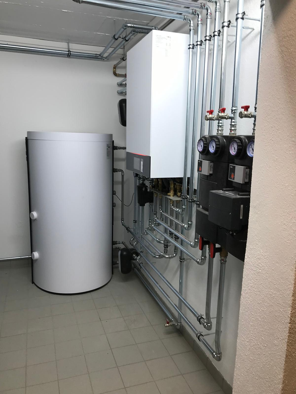 Warmwasserspeicher neben Wärmepumpen-Inneneinheit und Pumpengruppen